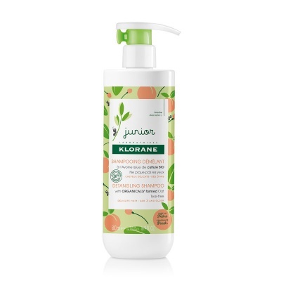 Frasco branco de shampoo Klorane Junior com tampa verde e rótulo com ilustrações de folhas e frutas.