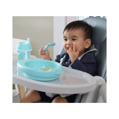 Bebé sentado numa cadeira de alimentação com prato e colher azuis e copo azul claro