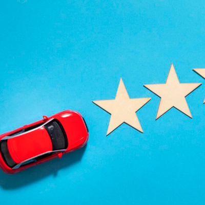 Carro de brinquedo vermelho e estrelas de cartão sobre fundo azul