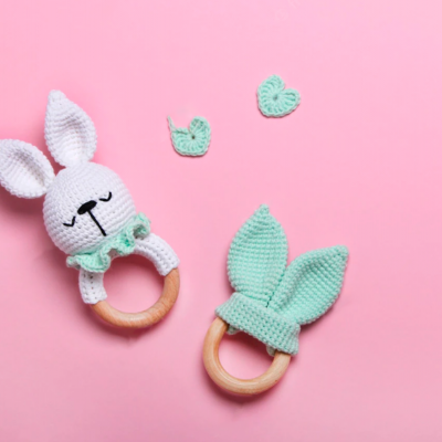 Chupetas de crochê com argolas de madeira em fundo rosa