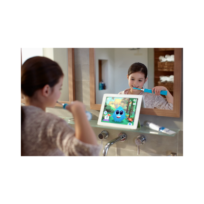 Criança a escovar os dentes com escova azul e tablet com personagem animado na casa de banho