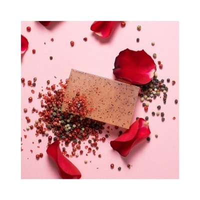 Sabonete castanho com partículas rodeado por pétalas vermelhas e pimenta colorida
