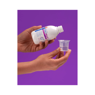 Mãos segurando garrafa branca CURAPROX e copo medidor transparente com líquido