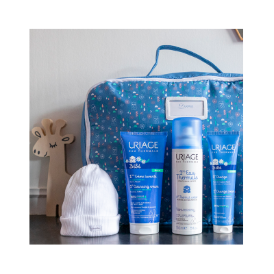 Kit de produtos para bebé Uriage com bolsa azul estampada, três tubos e gorro branco