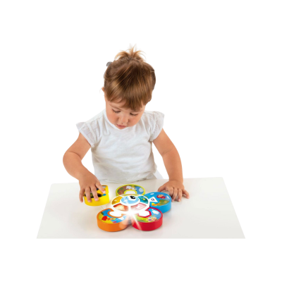 Criança a brincar com brinquedo colorido em forma de flor sobre mesa branca