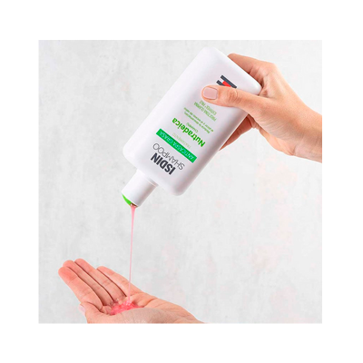 Frasco branco de champô ISDIN a verter líquido cor-de-rosa na mão