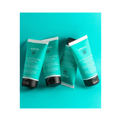 Quatro tubos de creme condicionador APIVITA verde azulados sobre fundo turquesa