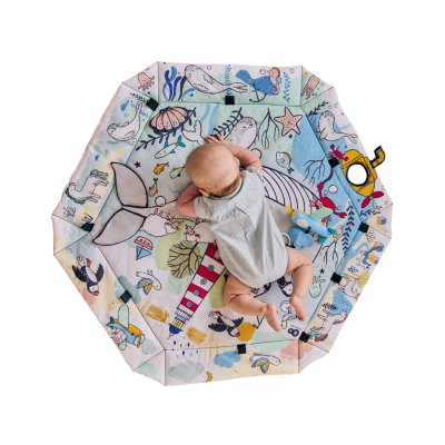 Tapete de brincadeira octogonal com desenhos marinhos coloridos e bebé deitado em cima