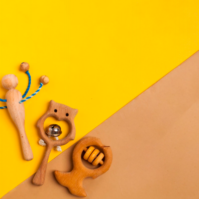 Três instrumentos de madeira para massagem ou brinquedo sobre fundo amarelo e castanho.