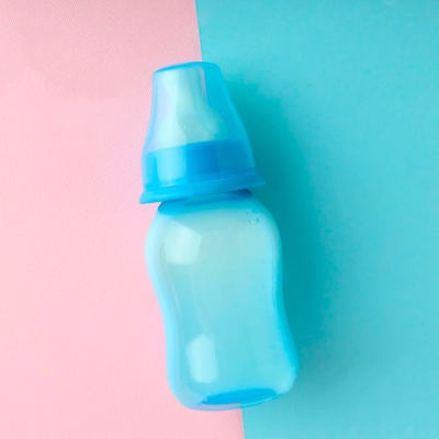 biberão azul de plástico em fundo rosa e azul
