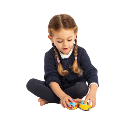 Menina sentada com suéter azul e leggings pretas brincando com carrinhos de brinquedo coloridos.
