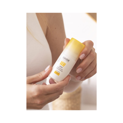 Mãos segurando desodorizante BABE com tampa amarela em ambiente claro