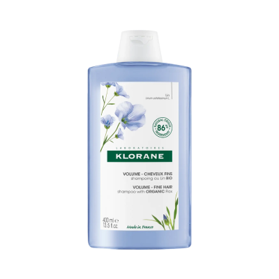 Frasco de champô Klorane azul translúcido com rótulo de flores azuis e texto branco.