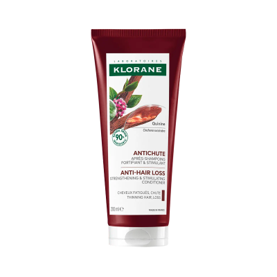 Condicionador anticaspa Klorane em tubo vermelho com rótulo branco e imagem de plantas.