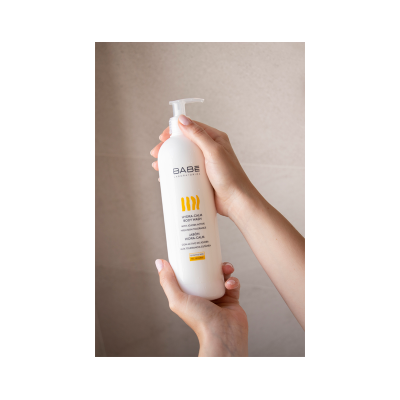 Frasco branco com doseador de gel de banho BABÉ HYDRA-CALM segurado por mãos