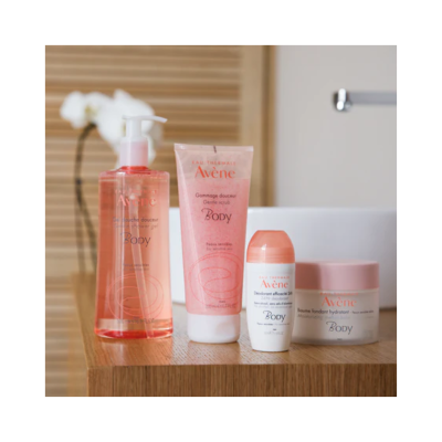 Produtos Avène para corpo em diferentes embalagens rosa e branco sobre mesa de madeira.