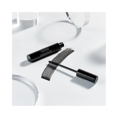 Máscara de pestanas Couvrance preta com aplicador e traço preto sobre superfície branca.