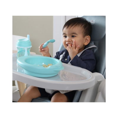 Criança em cadeira alta Chicco com prato e colher azul e copo de bebé