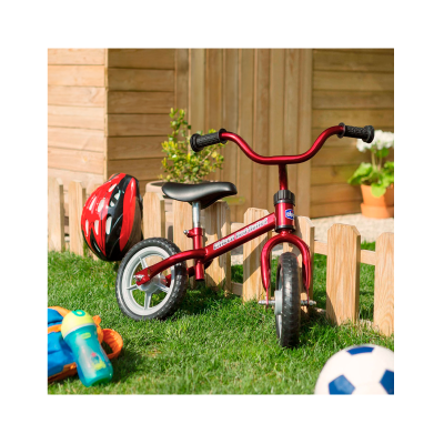 Bicicleta infantil vermelha com capacete e bola no jardim