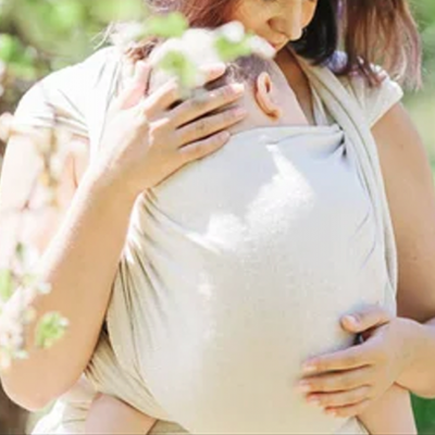 Mulher a usar faixa de transporte de bebé cinzento claro ao ar livre