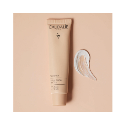 Tubo de creme facial Caudalie Vinocrush com textura do creme em fundo bege claro