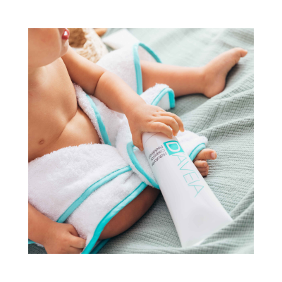 Bebé com roupão branco e tubo de creme DAVEIA