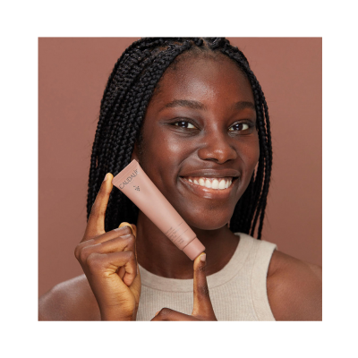 Mulher negra com tubo de creme CAUDALÍE cor rosa