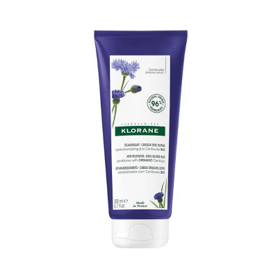 Tubo de creme Klorane com flor azul na embalagem roxa e branca
