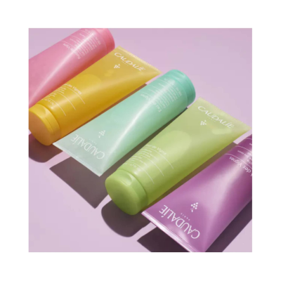 Tubos coloridos de produtos CAUDALIE sobre superfície lilás
