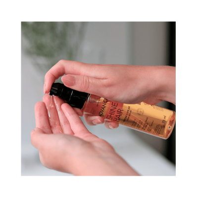 Frasco de líquido para cabelo sendo aplicado nas mãos