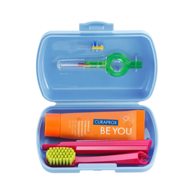 Conjunto de higiene dental em caixa azul com escova rosa, pasta Curaprox BE YOU e utensílios de limpeza.
