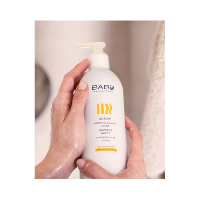 Frasco branco de sabonete líquido com doseador sendo segurado por mãos molhadas