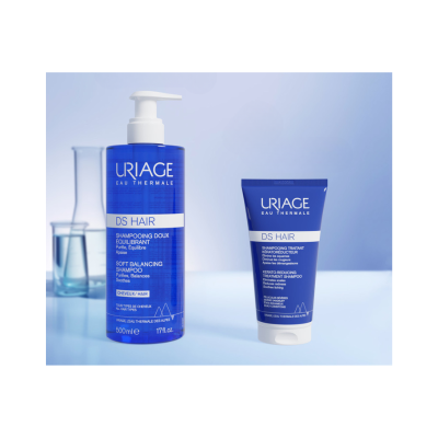 Dois produtos Uriage DS Hair com embalagem azul e texto branco, sobre superfície azul clara.