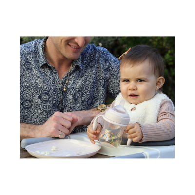 Copo de treino infantil transparente com bico e pegas, segurado por bebé em cadeirão