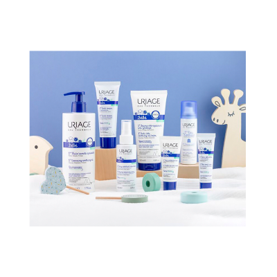 Produtos de cuidado bebé URIAGE em embalagens brancas e azuis sobre superfície branca com decoração infantil