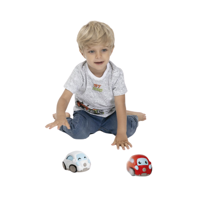 Camisola branca com padrão de texto cinzento e estampado colorido OFF ROAD, calças de ganga, menino sentado no chão com dois carros de brinquedo azul claro e vermelho