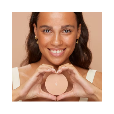 Mulher sorridente segurando produto redondo cor de pele com símbolo de uvas