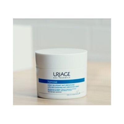 Pote branco de creme Uriage Xémose sobre superfície clara