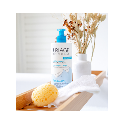 Frasco de creme lavante Uriage com esponja e toalha numa banheira