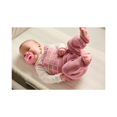 Bebé deitado com roupa de malha rosa e chupeta rosa