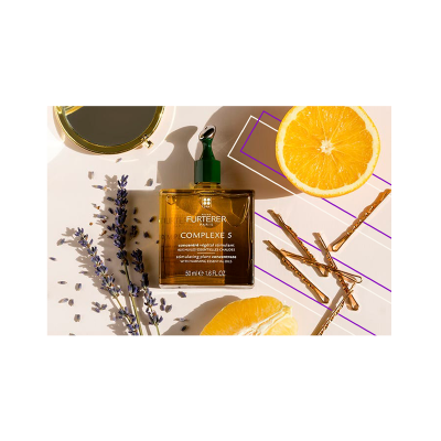 Frasco âmbar de produto capilar com raminhos de lavanda, laranja e paus de canela