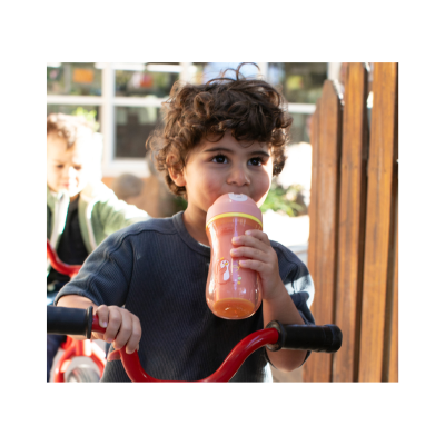 Copo de treino cor de laranja com tampa rosa e pinguim, criança a segurar e bicicleta vermelha