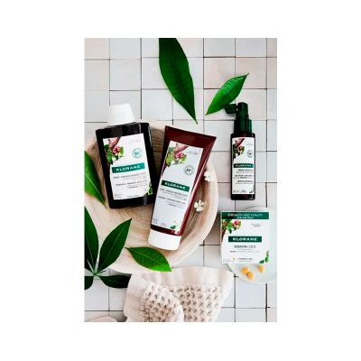 Produtos Klorane numa composição com folhas verdes e fundo de azulejos