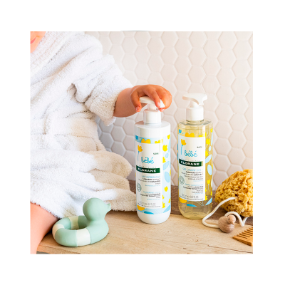 Dois produtos para bebé Klorane com embalagem branca e transparente e padrão de flores amarelas