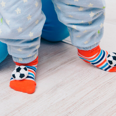 Meias coloridas de bebé com bola de futebol e calças azuis com estrelas