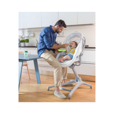 Cadeira de papa branca com estrutura cinza claro e bebé sentado a ser alimentado por adulto numa cozinha