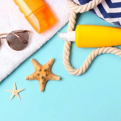 Produtos de praia sobre fundo azul, óculos de sol, embalagem amarela, toalha branca e estrelas-do-mar.