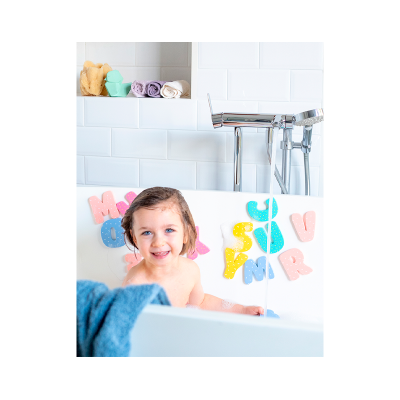 Criança numa banheira branca com letras de espuma e toalhas enroladas em prateleira