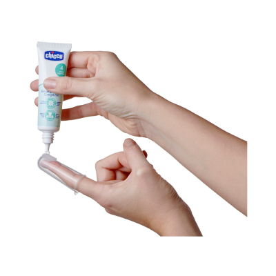 Duas mãos aplicando creme gengival em gel Chicco numa escova de dedo transparente.