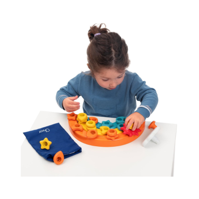 Criança brinca com jogo de encaixe colorido em mesa branca